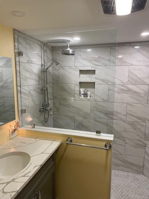 bathroom with a tile shower and vanity