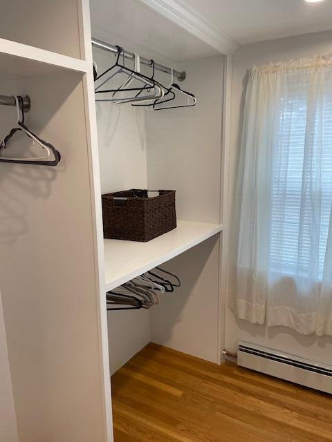 walk in closet featuring baseboard heating and hardwood / wood-style floors