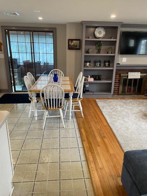 dining area with a brick fireplace, hardwood / wood-style flooring, and built in features