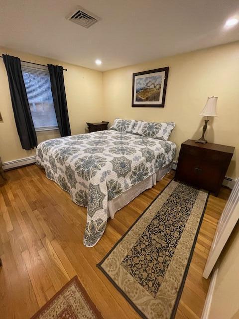 bedroom with a baseboard heating unit and light hardwood / wood-style floors