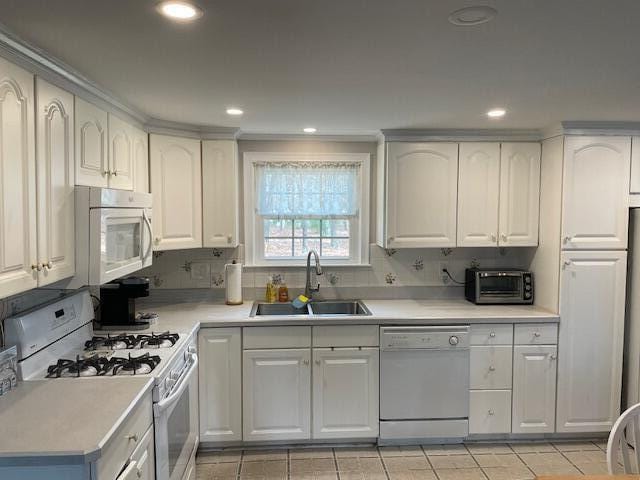 kitchen featuring white cabinetry, sink, white appliances, and decorative backsplash