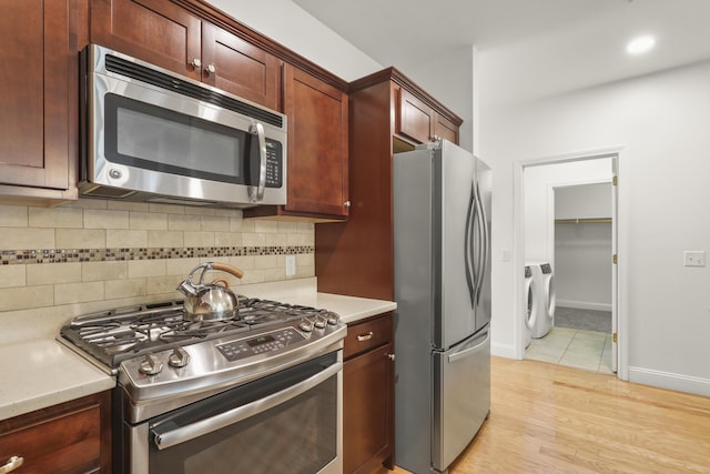 21 Grey Hawk Dr, Mashpee, MA 02649 - kitchen with appliances with stainless steel finishes, light countertops, decorative backsplash, light wood-style flooring, and washer / clothes dryer