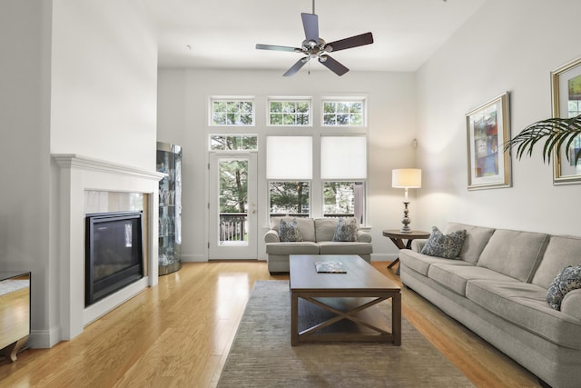 21 Grey Hawk Dr, Mashpee, MA 02649 - living room with wood finished floors, a glass covered fireplace, ceiling fan, baseboards, and a towering ceiling