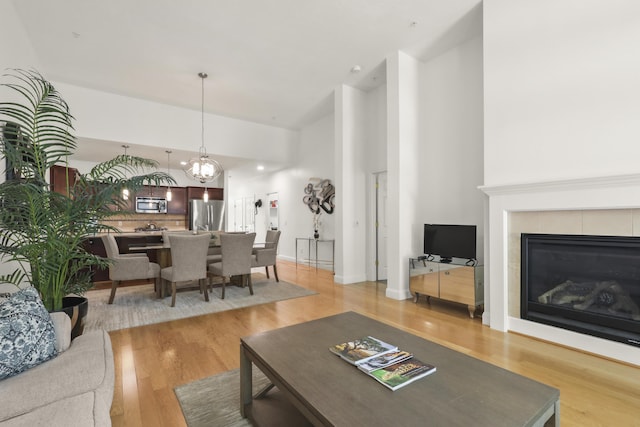 21 Grey Hawk Dr, Mashpee, MA 02649 - living area featuring light wood finished floors, a tile fireplace, a chandelier, and a high ceiling