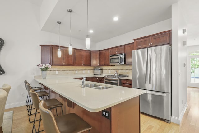 21 Grey Hawk Dr, Mashpee, MA 02649 - kitchen with stainless steel appliances, light wood-type flooring, light countertops, a breakfast bar area, and decorative backsplash