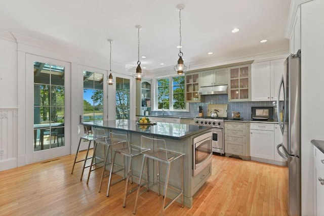 14 Indian Trl, Osterville, MA 02655 - kitchen with stainless steel appliances, under cabinet range hood, a breakfast bar, backsplash, and light wood-style flooring