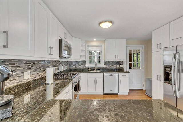 kitchen with sink, white cabinets, stainless steel appliances, and dark stone counters