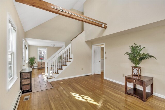 entryway featuring high vaulted ceiling, a baseboard heating unit, and light wood-type flooring