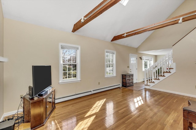 living room featuring light wood-type flooring, a baseboard heating unit, and lofted ceiling with beams