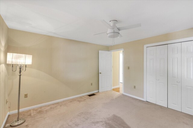 unfurnished bedroom featuring ceiling fan, light colored carpet, and a closet