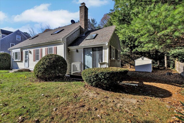 back of house with a storage unit and a yard