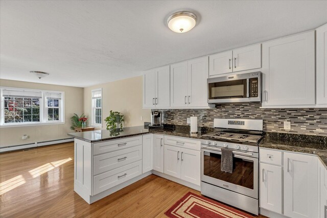 kitchen featuring white cabinets, kitchen peninsula, a baseboard heating unit, and stainless steel appliances