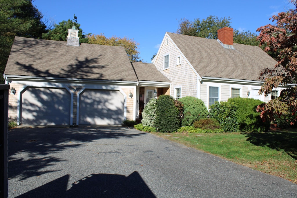 cape cod home featuring a garage