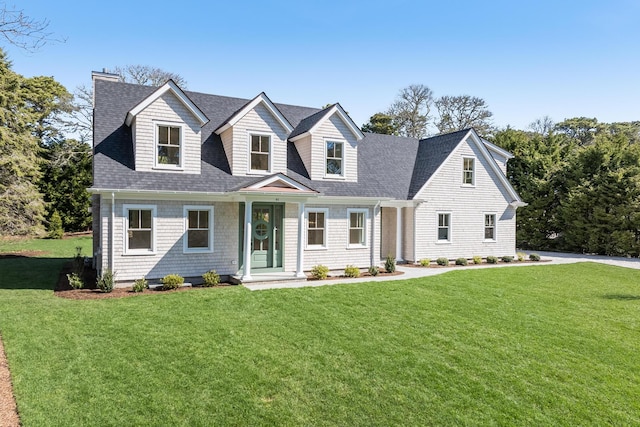 new england style home featuring gravel driveway, an attached garage, fence, a front lawn, and roof with shingles