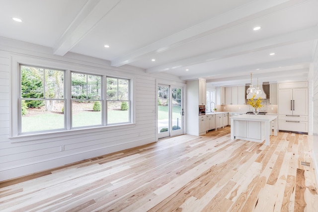unfurnished living room with light wood-type flooring, beamed ceiling, a sink, and recessed lighting