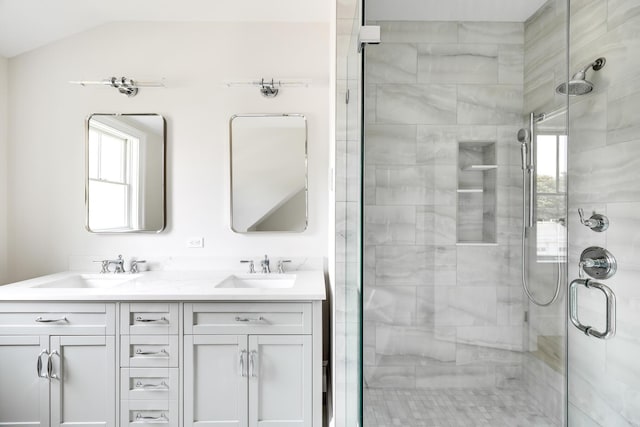 bathroom featuring vaulted ceiling, a shower with shower door, and vanity