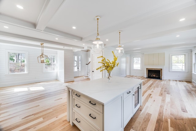 kitchen with hanging light fixtures, a center island, open floor plan, beamed ceiling, and light wood finished floors