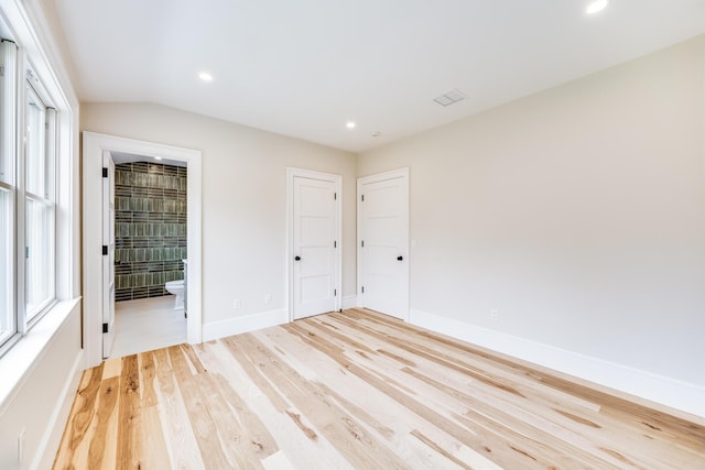 unfurnished bedroom featuring multiple windows, baseboards, light wood finished floors, and recessed lighting