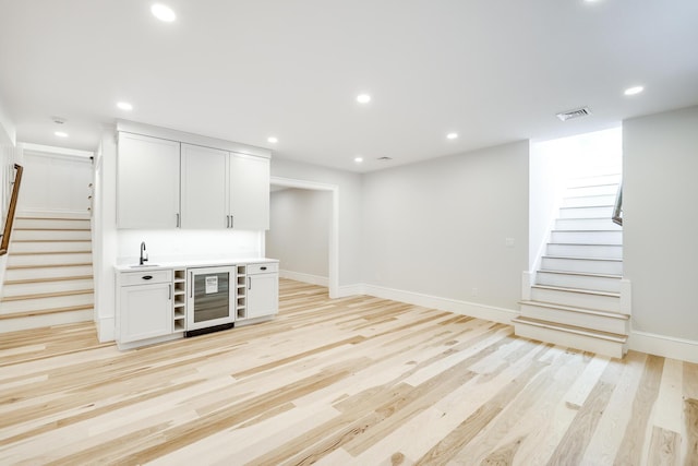 interior space with sink, white cabinets, light hardwood / wood-style flooring, and wine cooler