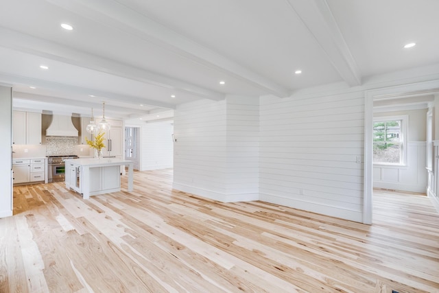 unfurnished living room with beam ceiling, light wood-type flooring, and recessed lighting