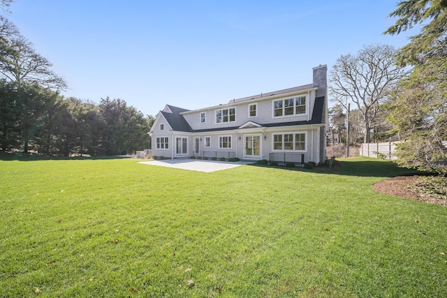 rear view of house featuring a patio, a shingled roof, entry steps, and a lawn