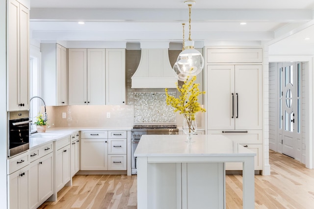 kitchen with high end range, a sink, custom exhaust hood, and light wood-type flooring