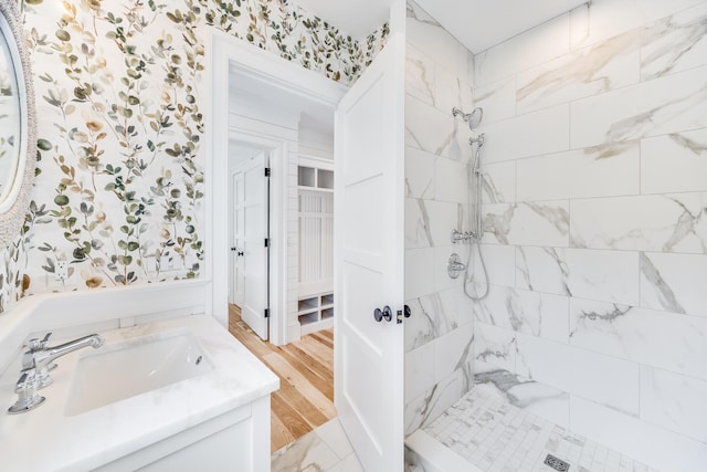 full bathroom featuring baseboards, a freestanding bath, a sink, double vanity, and wood finished floors