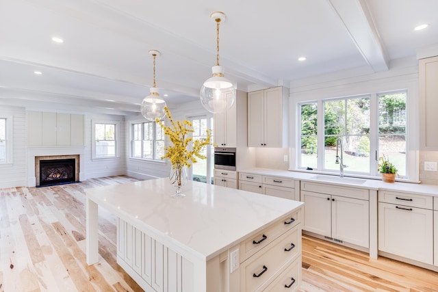 kitchen with custom exhaust hood, high end range, tasteful backsplash, light wood-style flooring, and a sink