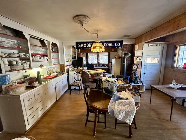 kitchen featuring wood finished floors, light countertops, open shelves, a wood stove, and pendant lighting