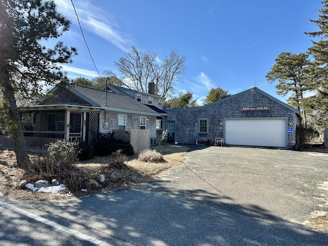 view of front of house with a garage, aphalt driveway, and a chimney