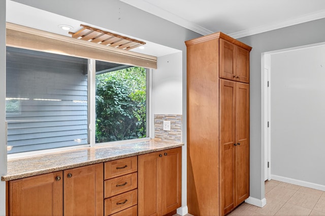 87 Susanna Dr, Brewster, MA 02631 - kitchen with light stone countertops, light tile patterned floors, ornamental molding, brown cabinetry, and backsplash