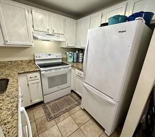 4 Westcliff Dr Unit 4, Cedarville, MA 02360 - kitchen with white cabinets, under cabinet range hood, white appliances, light tile patterned flooring, and light stone countertops