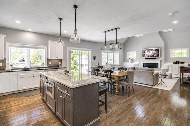 41 Old Main Rd Unit 3Au, North Falmouth, MA 02556 - kitchen with a sink, a kitchen breakfast bar, open floor plan, a fireplace, and white cabinets