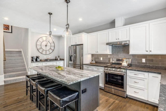 41 Old Main Rd Unit 3Au, North Falmouth, MA 02556 - kitchen with appliances with stainless steel finishes, under cabinet range hood, white cabinetry, dark wood-style floors, and dark stone counters