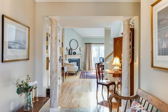 hall with light wood-style floors and decorative columns