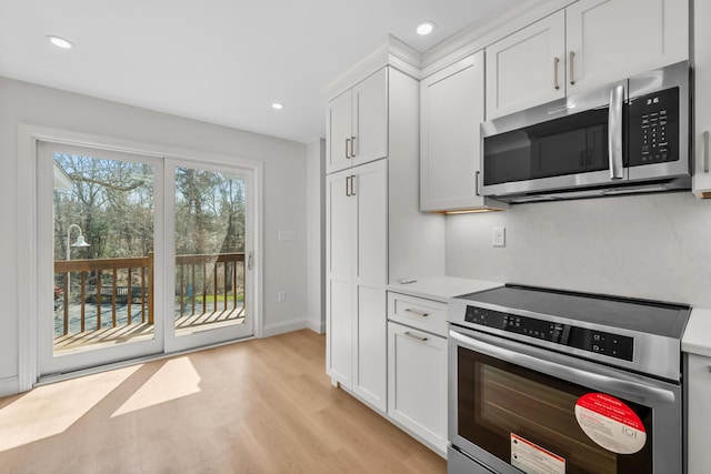 kitchen featuring light wood-style floors, recessed lighting, light countertops, white cabinets, and stainless steel appliances