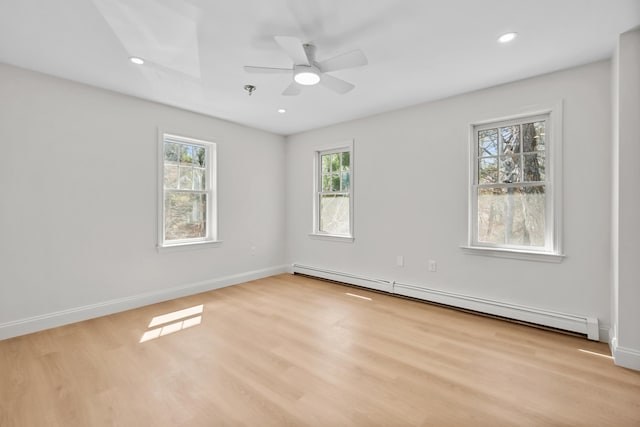 unfurnished room featuring baseboards, a baseboard heating unit, and light wood-style flooring
