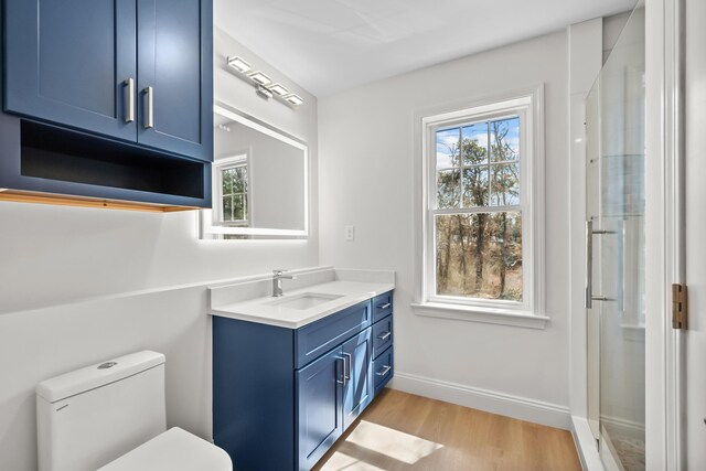 full bath featuring vanity, wood finished floors, toilet, baseboards, and an enclosed shower