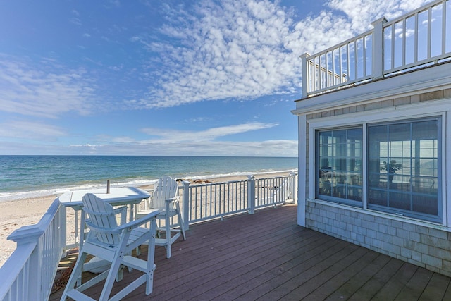 wooden terrace featuring a water view and a beach view