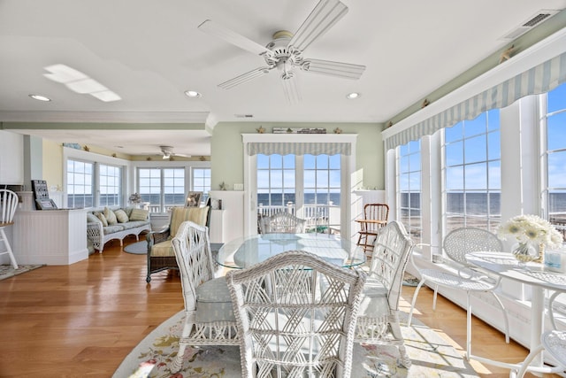 sunroom with ceiling fan and a water view