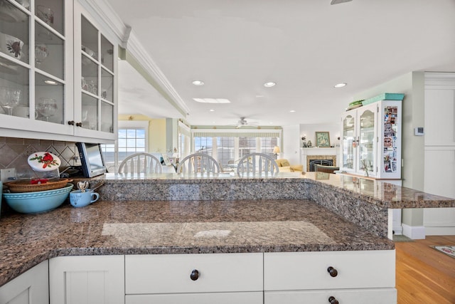 kitchen with light wood-type flooring, backsplash, white cabinetry, and crown molding