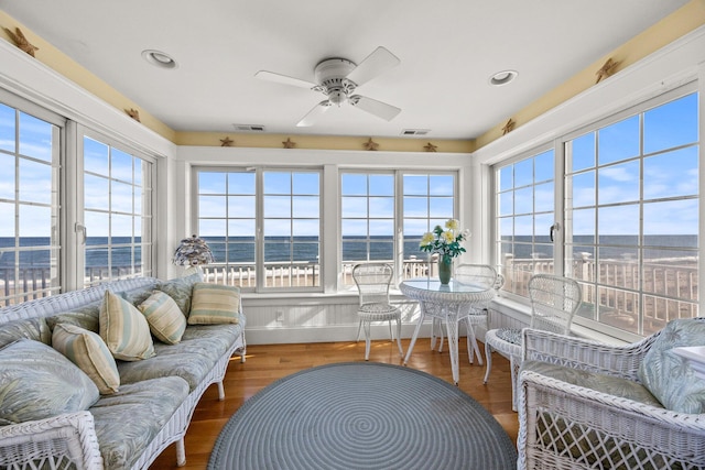 sunroom with a water view and ceiling fan