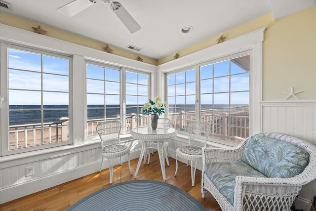 sunroom / solarium featuring ceiling fan and a water view