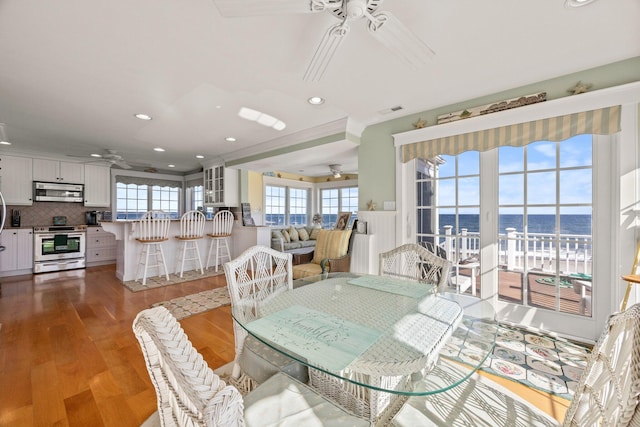 dining room with ceiling fan, hardwood / wood-style flooring, and a water view