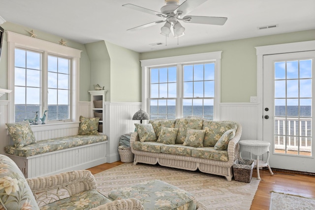 interior space with ceiling fan, a water view, light hardwood / wood-style flooring, and a wealth of natural light