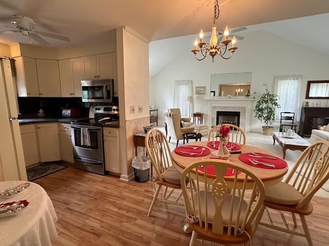 481 Buck Island Rd Unit 17Fa, West Yarmouth, MA 02673 - dining area featuring a fireplace, a chandelier, light wood-style floors, ceiling fan, and lofted ceiling