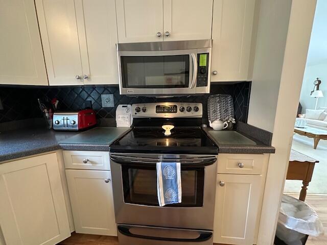 481 Buck Island Rd Unit 17Fa, West Yarmouth, MA 02673 - kitchen featuring appliances with stainless steel finishes, white cabinets, dark countertops, and decorative backsplash