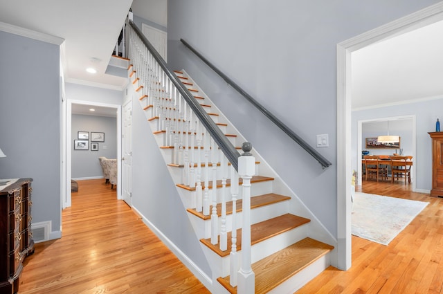 stairs featuring ornamental molding and hardwood / wood-style floors