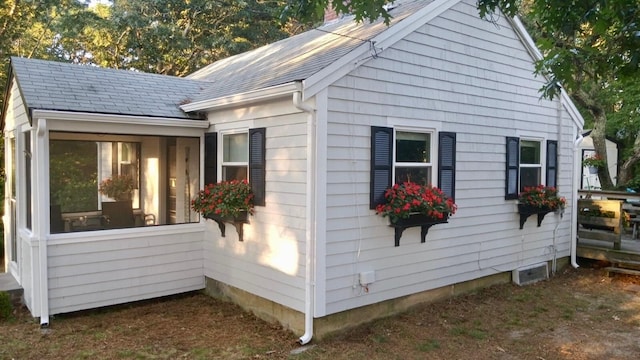 view of side of property featuring a sunroom and roof with shingles