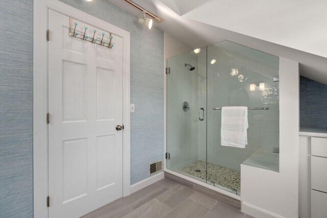 bathroom with vaulted ceiling and a shower with door